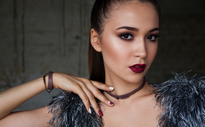 Female fashion model with olive complexion maroon lipstick and dark eyes gazing directly at viewer